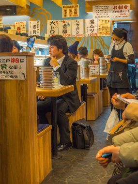 Tokyo, Japonya -28 Haziran 2017: kimliği belirsiz kişi bir kaitenzushi Konveyör bant suşi restoranı, Tokyo içinde bir tablo üzerinde bir çeşitli japanesse yemek yeme