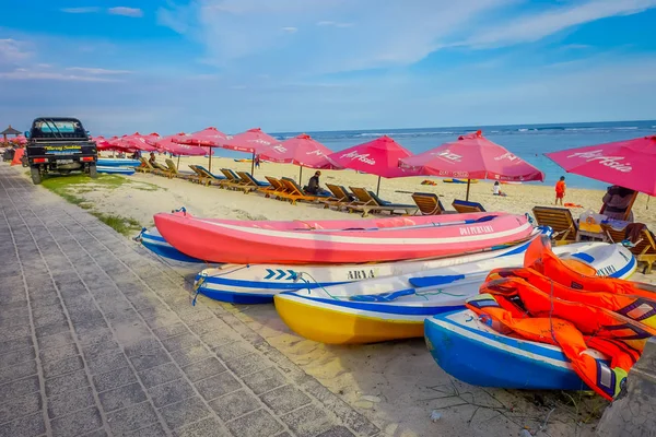 BALI, INDONESIA - 11 MARZO 2017: Bella giornata di sole con una fila di ombrelloni rossi e alcune barche sulla sabbia gialla, nella spiaggia di Pantai pandawa, nell'isola di Bali, Indonesia — Foto Stock