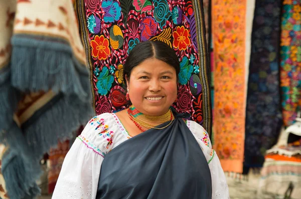 OTAVALO, ECUADOR - MAIO 17, 2017: Close up de uma mulher indígena hispânica não identificada vestindo roupas e colar tradicionais andinos, posando para câmera em fundo de tecidos coloridos — Fotografia de Stock