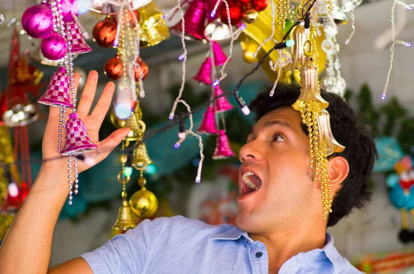 QUITO, ECUADOR- 07 MAIO, 2017: Feche-se um belo jovem assistindo bela e colorida decoração de árvore de natal em um mercado — Fotografia de Stock