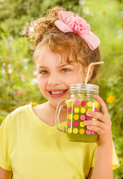 Mooi jong meisje met een geel t-shirt, houden van een gezonde smoothie drankje gemaakt van super foods, fruit, noten, bessen — Stockfoto