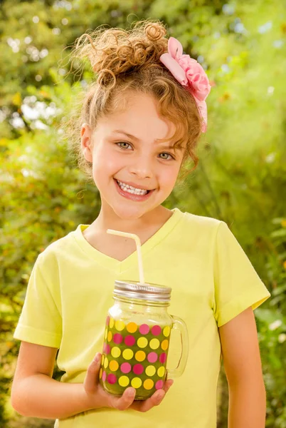Hermosa joven con una camiseta amarilla, sosteniendo un batido saludable bebida hecha de súper alimentos, frutas, nueces, bayas —  Fotos de Stock