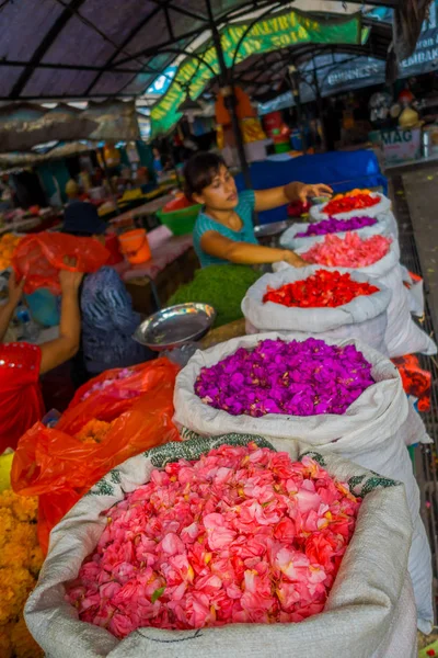 Bali, Endonezya - 08 Şubat 2017: Açık havada Bali çiçek kimliği belirsiz kişi Pazar, üst üste ağırladı beyaz çuval içinde renkli çiçeklerle, çiçekler de sembolik teklifleri olarak kullanılır