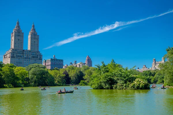 New York, USA - 22. November 2016: Eine unbekannte Gruppe von Menschen paddelt an einem schönen sonnigen Tag auf dem See im Central Park, dahinter ein riesiges Gebäude in New York — Stockfoto