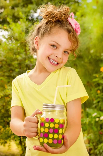 Hermosa joven con una camiseta amarilla, sosteniendo un batido saludable bebida hecha de súper alimentos, frutas, nueces, bayas —  Fotos de Stock