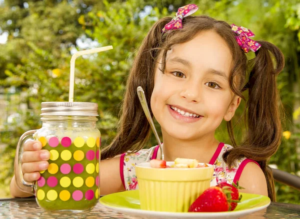 Primer plano de una hermosa joven, preparándose para comer una ensalada de frutas saludables y una bebida saludable en un fondo de jardín —  Fotos de Stock