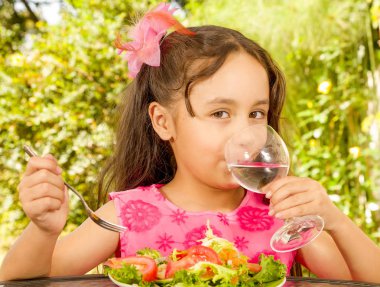 Bir bardak su içme ve sağlıklı bir salata, bir bahçe arka planda yiyecek hazırlama güzel kızın, yakın çekim