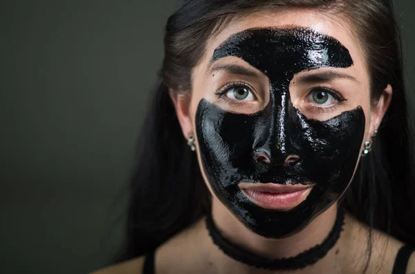 Närbild av en skönhet ung kvinna med en svart mask rengör huden — Stockfoto