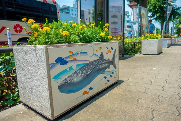 OSAKA, JAPÃO - JULHO 18, 2017: Feche um vaso pedrado com algumas flores amarelas e um belo desenho de um animal marinho no vaso de flores em Dowtown vista da paisagem urbana de Osaka na temporada de verão em — Fotografia de Stock