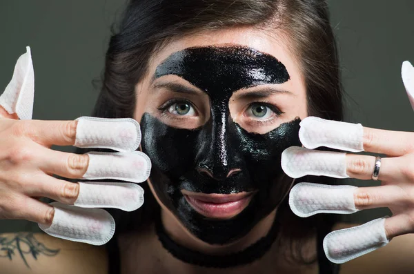 Close up of a beauty young woman using a black face mask and wearing nails protector in her nails, in a black background — Stock Photo, Image