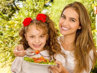 Güzel genç anne ve kızı sağlıklı bir salata yemeye hazırlanıyor