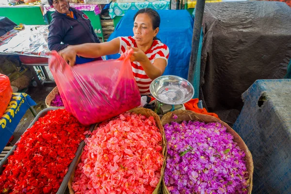 BALI, INDONESIA - MARCH 08, 2017: Unidentified people in outdoors Bali flower market. Flowers are used daily by Balinese Hindus as symbolic offerings at temples, inside of colorful baskets — Stock Photo, Image