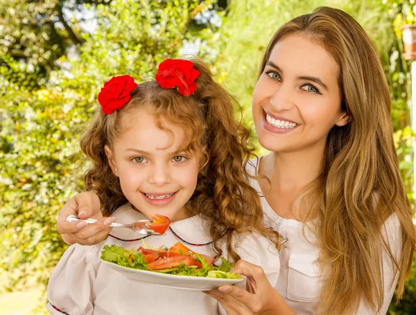 Güzel genç anne ve kızı sağlıklı bir salata yemeye hazırlanıyor — Stok fotoğraf