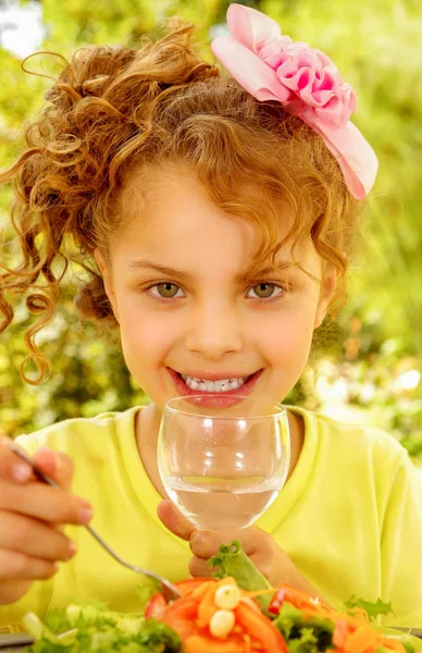 Belle jeune fille, vêtue d'un t-shirt jaune se préparant à manger une salade saine et à boire, dans un fond de jardin — Photo