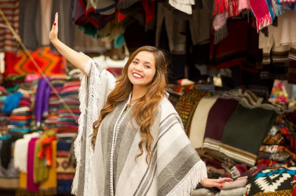 Schöne lächelnde junge Frau trägt eine traditionelle andine Kleidung und posiert für die Kamera, bunte Stoffe Hintergrund — Stockfoto
