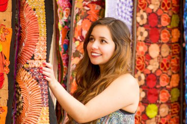 Güzel bir gülümseyen genç kadının and Giyim Tekstil iplik ve dokuma el ile geleneksel dokunmadan yakın yün, renkli kumaşlar arka planda