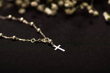 Rosary beads with blurred white small flowers, black background clipart