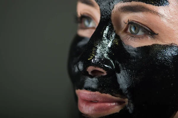 Close up de uma beleza jovem mulher usando uma máscara preta para limpar a pele — Fotografia de Stock