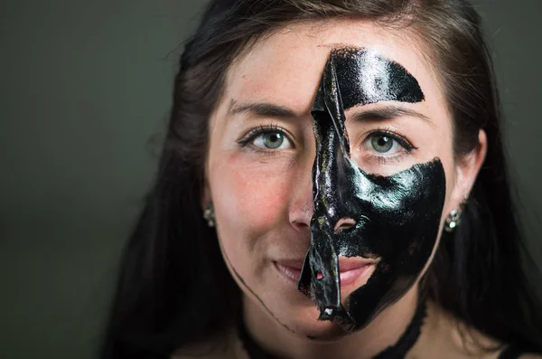 Primer plano de una joven belleza quitándose la mitad de una mascarilla negra — Foto de Stock