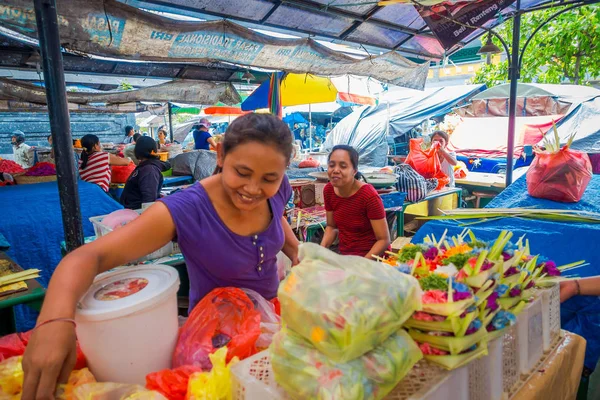 Bali, Endonezya - 08 Şubat 2017:'de bir tabloda Endonezya Denpasar şehir bir pazarda yapılmış bir kutusunun içinde çiçek tanzimi yapraklar kimliği belirsiz bir kadın yapmak