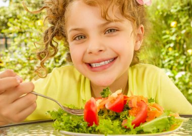 Bir bahçe arka planda bir çatal ile sağlıklı bir salata yemeye hazırlanıyor sarı bir tişört giyen güzel kızın yakın çekim