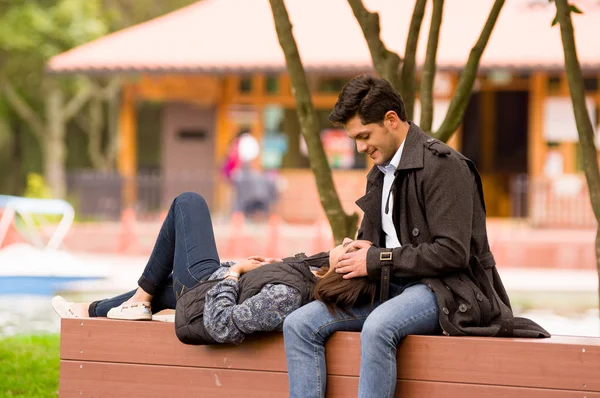 Vackra unga par i kärlek i st alla hjärtans dag, kvinna recumbent i hans pojkvän ben, i park — Stockfoto