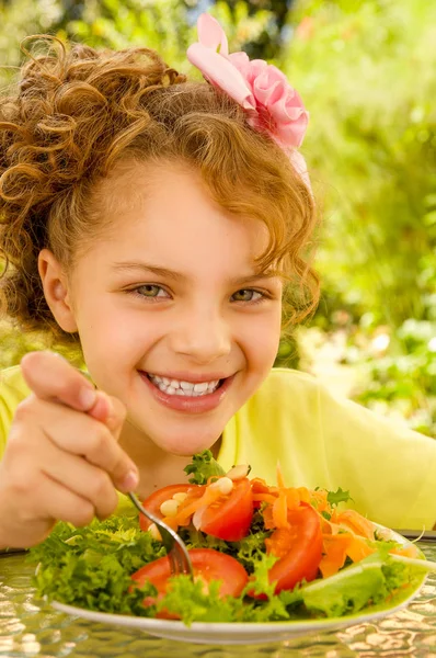 Primer plano de la hermosa chica, con una camiseta amarilla que se prepara para comer una ensalada saludable con un tenedor, en un fondo de jardín —  Fotos de Stock