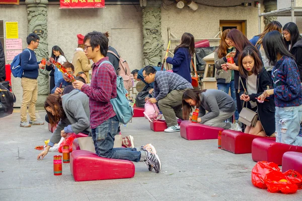 Hong Kong, Çin - 22 Ocak 2017: Wong Tai Sin Budist tapınağı içinde kırmızı bir yumuşak yastık onların diz üzerinde dua dua, Hong Kong, Çin'de kimliği belirsiz kişi