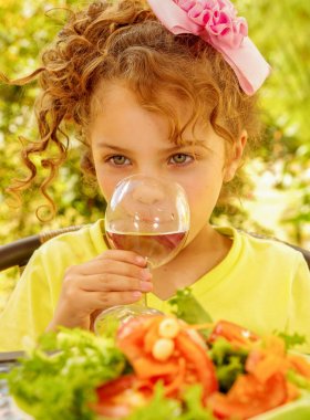 Bir bardak su içme ve Bahçe arka planda sağlıklı bir salata yemeye hazırlanıyor sarı bir tişört giyen güzel genç kız