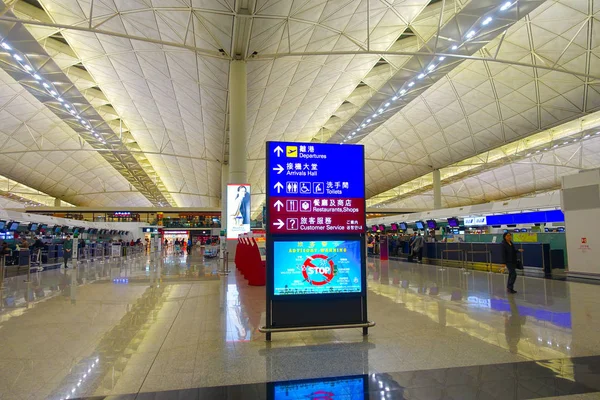 Hong Kong, China - 26 januari 2017: Niet-geïdentificeerde mensen lopen in de buurt van informatieve teken binnenkant van de luchthaven van Hong Kong — Stockfoto