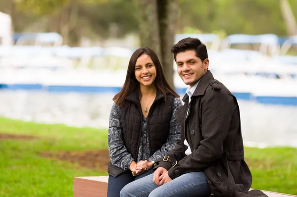 Close up of a beautiful smiling young couple in love in st valentines day and looking at camera, sitting in a park — Stock Photo, Image