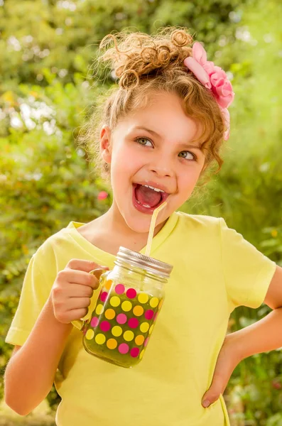 Beautiful young girl wearing a yellow t-shirt, having a good morning healthy smoothie drink made of super foods, fruits, nuts, berries — Stock Photo, Image