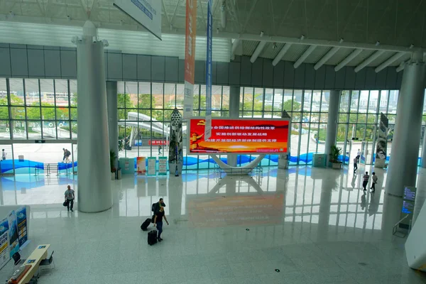 Шэньчжэнь, Китай - 11 мая 2017 года: Неизвестные гуляют со своими чемоданами внутри удивительной архитектуры здания терминального парома в городе Шэньчжэнь Китай — стоковое фото