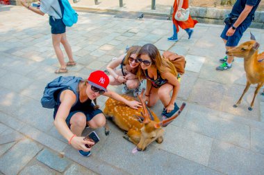 Nara, Japonya - 26 Temmuz 2017: kimliği belirsiz kadın vahşi bir geyik Nara, Japonya'nın bir selfie alarak, yakın çekim. Nara, Japonya - eski düşen şehir ve şu anda Unesco Dünya bir büyük turizm yer 