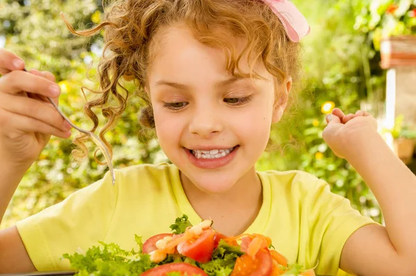 Primer plano de la hermosa chica, con una camiseta amarilla que se prepara para comer una ensalada saludable con un tenedor, en un fondo de jardín —  Fotos de Stock