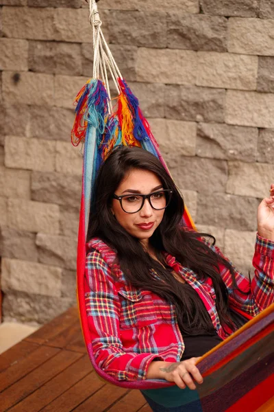 Mooie jonge vrouw ontspannen en liggend in een kleurrijke hangmat en genieten van het leven — Stockfoto