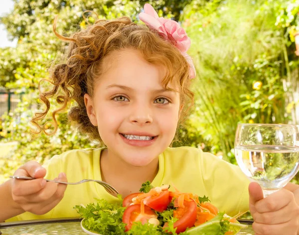 Close up van mooi meisje, met een geel t-shirt voorbereidingen voor een gezonde salade eet en drink een glas water, in een tuin achtergrond — Stockfoto