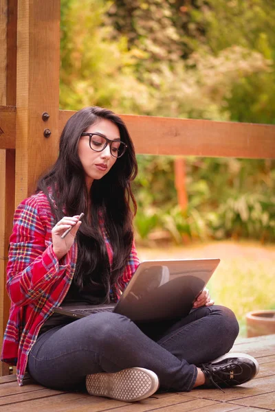 Cool hipster student kobieta nosi okulary okulary. Kaukaski kobiece kobieta studentka szuka i jej komputer w plenerze, podwórku tło — Zdjęcie stockowe