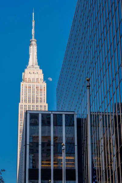 NEW YORK, États-Unis - 22 NOVEMBRE 2016 : Bâtiment avec l'Empire State Building en arrière-plan, il a été le plus haut bâtiment du monde pendant plus de 40 ans, de 1931 à 1972, avec la lune dans la — Photo