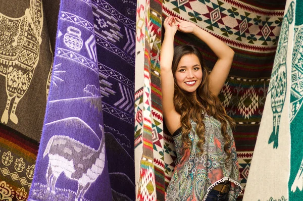 Güzel gülümseyen genç kadın and geleneksel giyim ve kamera, renkli kumaşlar arka plan için poz dokunmadan