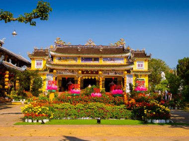 Hoian, Vietnam, Eylül, 04 2017: Güneşli bir günde Vietnam hoian adlı renkli çiçekli güzel bir jarden ile antik bir tapınak görünümünü
