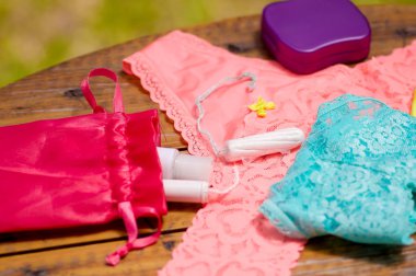 İn yakın bir pembe ve mavi kadın iç çamaşırı ve ahşap bir masa ve arka plan bulanık içinde mor bir plastik kutu kırmızı Pamuk Çanta üzerinde bir adet pamuk tampon