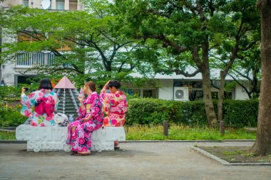Tokyo, Japonya Haziran 28-2017: tanımlanamayan grup giyen bir kimono elbise ve alma selfies için theirself, Budist tapınağı Sensoji Tokyo parkının bir beyaz genel sandalyede oturan kadın