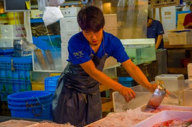 Tokyo, Japonya Haziran 28-2017: buz Tsukiji Balık pazarı, metalik bir pot ile toptan Tokyo Japonya, Tsukiji piyasa manipüle mavi elbise ve delantal, kimliği belirsiz biri en büyük