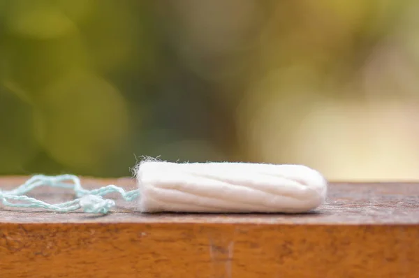 Producto de higiene femenina - tampón de algodón de menstruación sobre una estructura de madera, en un fondo borroso —  Fotos de Stock