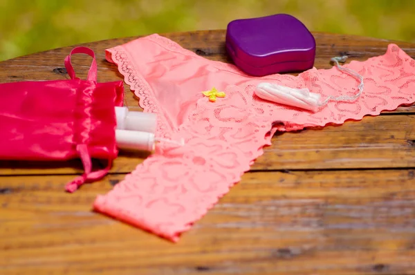 クローズ アップ、ピンク女性下着と赤いコットン バッグ、木製のテーブルや背景をぼかして、紫色のプラスチック ボックスに月経の綿のタンポン — ストック写真