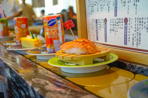 TOKIO, JAPÓN -28 JUN 2017: Primer plano de una variedad de comida japonesa sobre una mesa, dentro de un restaurante de sushi con cinta transportadora kaitenzushi en Tokio —  Fotos de Stock