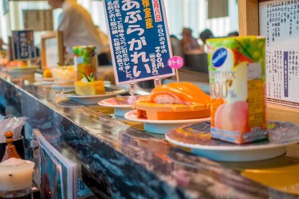 TOKIO, JAPÓN -28 JUN 2017: Primer plano de una variedad de comida japonesa sobre una mesa, dentro de un restaurante de sushi con cinta transportadora kaitenzushi en Tokio —  Fotos de Stock