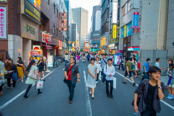 ТОКИО, ЯПОНИЯ 28 - 2017: Неопознанные люди, переходящие улицу с помощью пешеходного перехода в районе Икебукуро, Токио, Япония. Токио - и столица, и самый густонаселенный город
