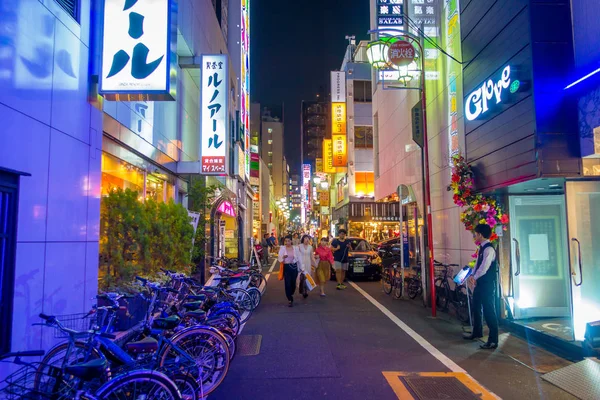 TOKYO, JAPON 28 JUIN 2017 : Des personnes non identifiées marchent et profitent du magnifique quartier des lumières rouges de Kabukicho, entouré de grands bâtiments et de publicités dans la nuit, situé à Tokyo — Photo